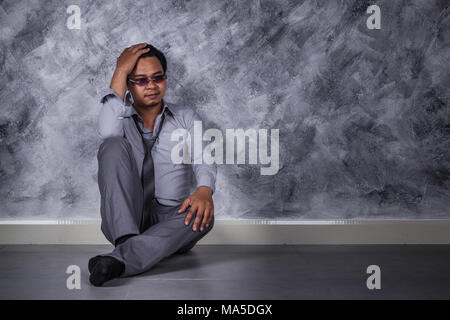 Junge gedrückt Geschäftsmann, sitzen auf dem Boden Stockfoto