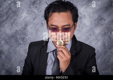 Junger Mann mit goldenen Bitcoin in der Hand Stockfoto