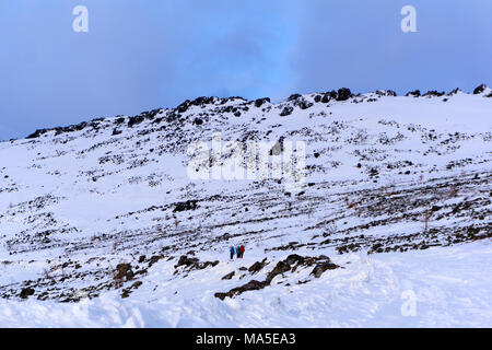 Gruppe der Wanderer auf einem schneebedeckten Berg Straße überqueren einer felsigen baumlosen Hang Stockfoto