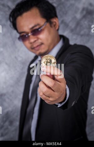 Junger Mann mit goldenen Bitcoin in der Hand Stockfoto