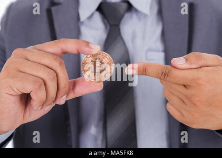 Bronze bitcoin in der Hand von Mann mit Anzug Stockfoto