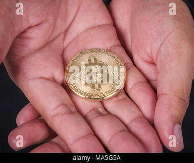 Gold bitcoin in der Hand des Menschen Stockfoto