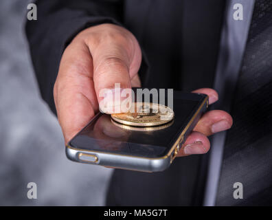 Nahaufnahme, Geschäftsmann mit bitcoin und über ein Mobiltelefon Stockfoto