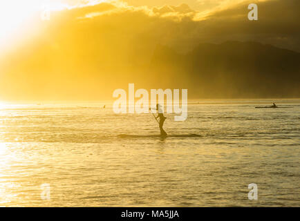 Stand up Paddler, bei Sonnenuntergang mit Moorea, die im Hintergrund arbeiten, Papeete, Tahiti, Französisch-Polynesien Stockfoto