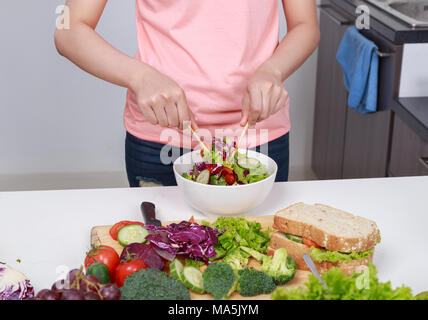Nahaufnahme junge Frau mischen Salat beim Kochen in der Küche Stockfoto