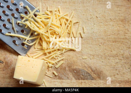 Nahaufnahme von geriebenem Käse und reibe liegen auf Holz Schneidebrett Stockfoto
