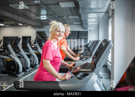 Portrait von lächelnden älteren Dame auf dem Laufband im Fitnessstudio Stockfoto