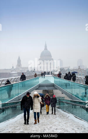 Die Millennium Bridge über die Themse und die Kuppel der St. Paul's Kathedrale in London im Schnee Stockfoto