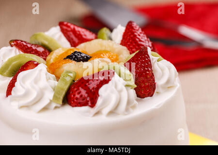 Eine Nahaufnahme von einem weißen Kuchen gekrönt mit verschiedenen Früchten. Stockfoto