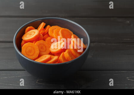 Geschnittene Karotten in einer Schüssel auf schwarzem Holz- Hintergrund Stockfoto