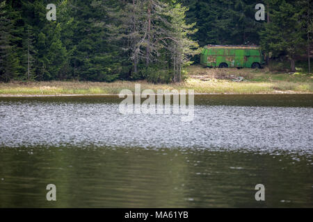 Alten rostigen Bus verwandelte sich in einen Lagerraum im Kiefernwald am Ufer des Sees von Shiroka Poljana in Rhodopen Gebirge, Bulgarien Stockfoto