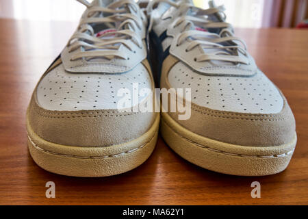 Vorderansicht des ein Paar Vintage White Sneaker Schuhe auf einer hölzernen Oberfläche Stockfoto