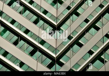 Abstrakte Sicht der modernen Glasfassade eines Hochhauses, die von einem kräftigen, Geometrie, Symmetrie und sattem grün Töne Stockfoto