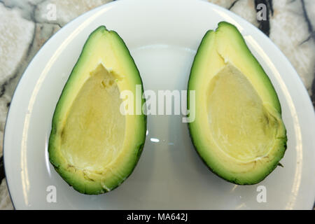 Zwei Scheiben Avocado auf weißem Hintergrund. Eine Scheibe mit Kern. Design Element für Etikett Stockfoto