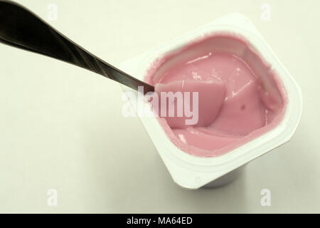 Erdbeer Joghurt aus weißem Kunststoff Schale auf hölzernen weißen Hintergrund. Erdbeer Joghurt. rosa Joghurt Stockfoto