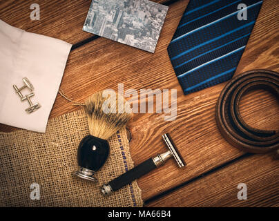 Herrenzubehör (Rasiermesser, Bürste, Krawatte, Karte, Manschettenknöpfe) auf dem Holztisch Stockfoto
