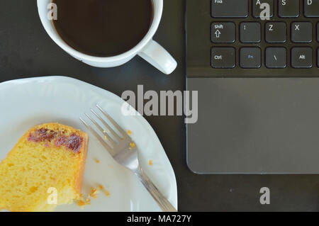 Maismehl Kuchen mit Guave Paste mit einem Biss, neben einer Tasse Kaffee und Teil eines Computers Tastatur von oben gesehen Stockfoto