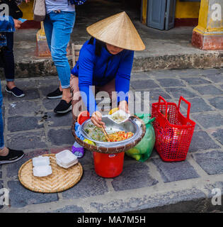 Typische vietnamesische Dame in konischer Hut mit Street Food durcheinen Wok Stockfoto