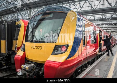 Eine Wache, die Signale, die als Fahrgäste rush für scheidende South Western Railway, Desiro City Class 707 Lokomotive. Stockfoto