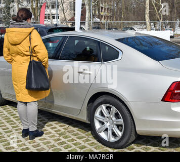 Frau, die neben einem Auto auf dem Parkplatz Stockfoto