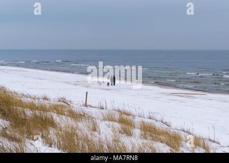 Leute, die Hunde am Strand mit Schnee in Palanga abgedeckt Stockfoto