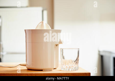 Elektrische Saftpresse und leeres Glas in einer modernen Küche Stockfoto