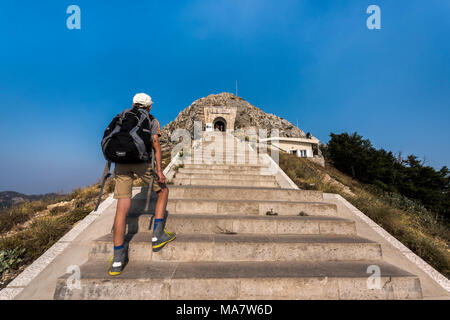 Njegusi Mausoleum in Nationalpark Lovcen - Junge touristische Junge mit Rucksack klettern die steile Treppe zum Eingang Stockfoto