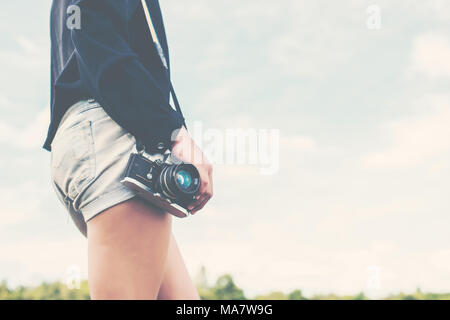 Schöne Frauen Fotografie stehend Hand retro Kamera in den Park. Stockfoto