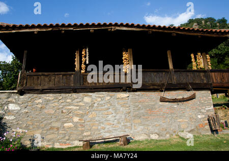 Geflechte der geernteten Zwiebeln hängen an ethno kleine Scheune Bauen mit Stein und Holz im Land Stockfoto