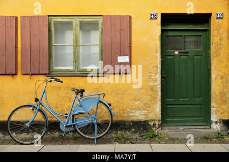 Blue Bicycle gegen gelbe Haus in Nyboder, Kopenhagen, Dänemark Stockfoto