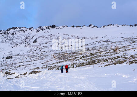 Gruppe der Wanderer auf einem schneebedeckten Berg Straße überqueren einer felsigen baumlosen Hang Stockfoto