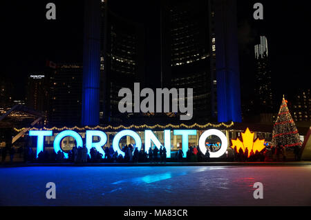 TORONTO, KANADA - 2018-01-01: Leute, die sich vor Toronto mit Weihnachtsbaum in der Nacht über die Eislaufbahn auf dem zentralen Nathan P Stockfoto