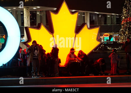 TORONTO, KANADA - 2018-01-01: torontonians vor der glühenden Maple Leaf, der kanadische Symbol, Rest nach Spaß auf der Eislaufbahn Stockfoto