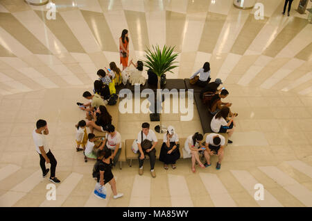 Menschen sitzen und am Treffpunkt warten und Menschen zu Fuß und mit Rolltreppe nach oben und unten für Shopping im Kaufhaus am 23. Mai 2017 Stockfoto