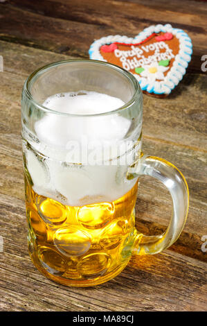 Grosses Glas gefüllt mit Bavarian Lager Bier und Souvenir Herz aus Oktoberfest Stockfoto