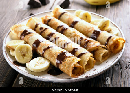 Nachtisch crepes Rolle mit bananenscheiben auf hölzernen Tisch. Nähe zu sehen. Stockfoto