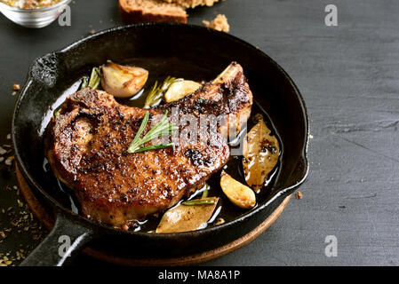 Schweinefleisch steak in der Pfanne auf schwarzem Hintergrund Stockfoto
