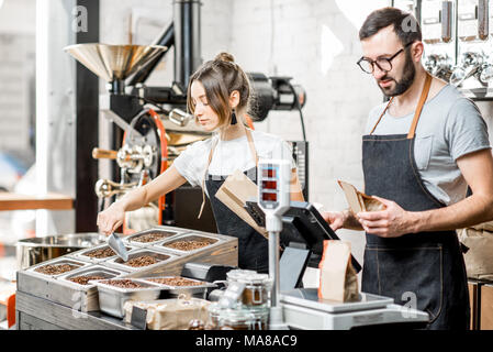 Zwei Verkäufer in Uniform Befüllen von Beuteln mit Kaffeebohnen arbeiten im Coffee Store Stockfoto