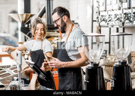 Zwei Verkäufer in Uniform Befüllen von Beuteln mit Kaffeebohnen arbeiten im Coffee Store Stockfoto