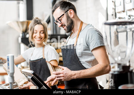 Zwei Verkäufer in Uniform Befüllen von Beuteln mit Kaffeebohnen arbeiten im Coffee Store Stockfoto