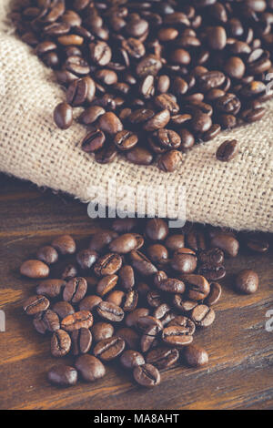 Kaffeebohnen auf Sackleinen, Stoff und Holz- Hintergrund Stockfoto