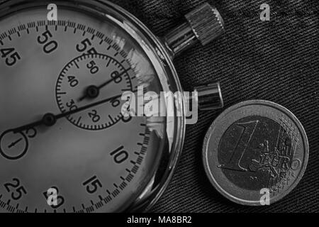 Euro Münze mit einem Nennwert von einem Euro und Stoppuhr auf dem alten Jeans Kulisse - Geschäft Hintergrund. Stockfoto
