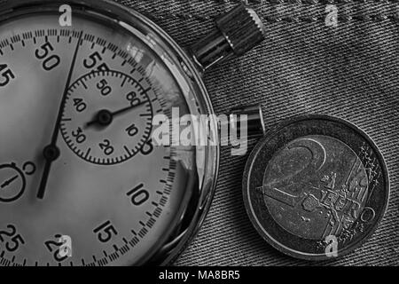 Euro Münze mit einer Stückelung von 2 Euro und die Stoppuhr auf abgenutzten denim Kulisse - Geschäft Hintergrund. Stockfoto