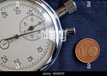 Euro Münze mit einer Stückelung von 1 Euro Cent und Stoppuhr auf dem alten blauen Jeans Hintergrund - Hintergrund Stockfoto