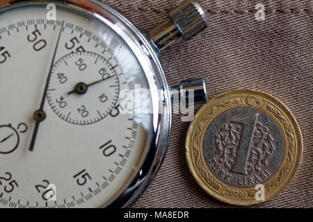 Türkische Münze mit einer Stückelung von 1 Lira und die Stoppuhr auf abgenutzten Beige Jeans Hintergrund - Hintergrund Stockfoto