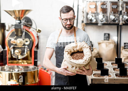 Porträt einer zwei glückliche Verkäufer in Uniform stehend mit Taschen voller Kaffeebohnen im Coffee Store Stockfoto