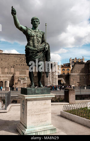 Statue des römischen Kaisers Augustus auf die Via dei Fori Imperiali, Rom mit dem Forum des Augustus im Hintergrund Stockfoto