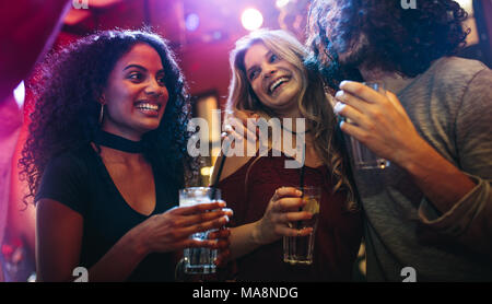 Glückliche junge Frauen feiern Freunde an der Bar. Eine Gruppe von Freunden eine gute Zeit im Nachtclub. Stockfoto