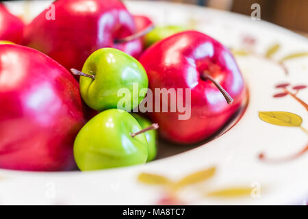 Makro Nahaufnahme von gefälschten Rote, grüne Äpfel bunte dekorative Platte auf Küche Esstisch in Staging Modell Wohnung Pile, home Stockfoto