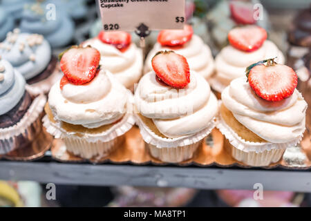 Makro Nahaufnahme von Vanille Erdbeer Muffins in Bäckerei in muffin Papier Büchsen mit weißen Frischkäse Puderzucker Glasur, Schneiden frische Beeren Stockfoto